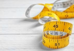 A yellow tape measure coiled on a white floor
