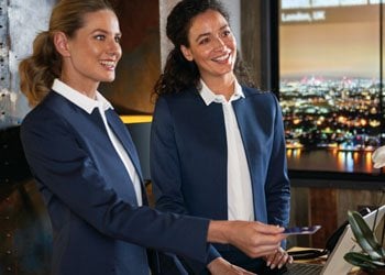 Two female receptionist in navy suit jackets and white shirts