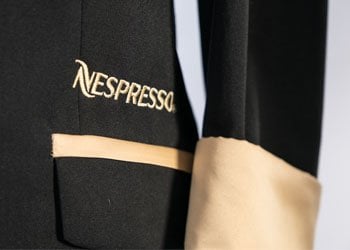 Close-up of Nespresso embroidery and bespoke tailoring on suit jacket