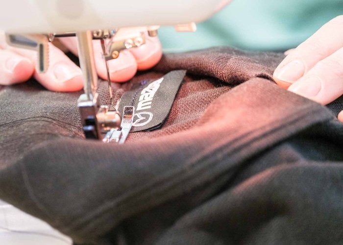 Mazda neck label being sewn on poloshirt