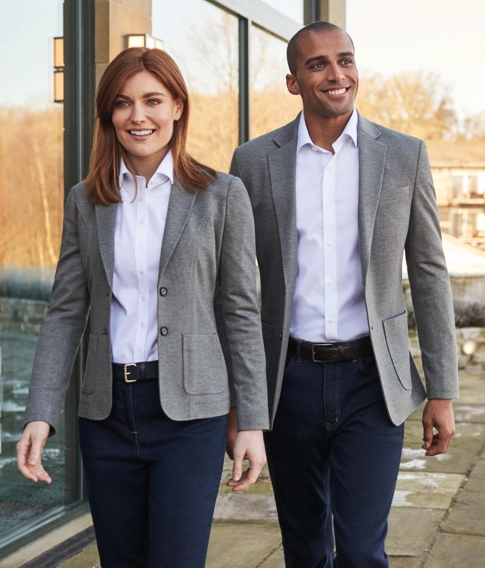A man and a woman in grey blazers walking down a street
